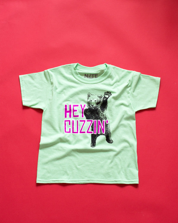 Youth t-shirt with cute waving bear, purple, white and black design on a bright mint T-Shirt.