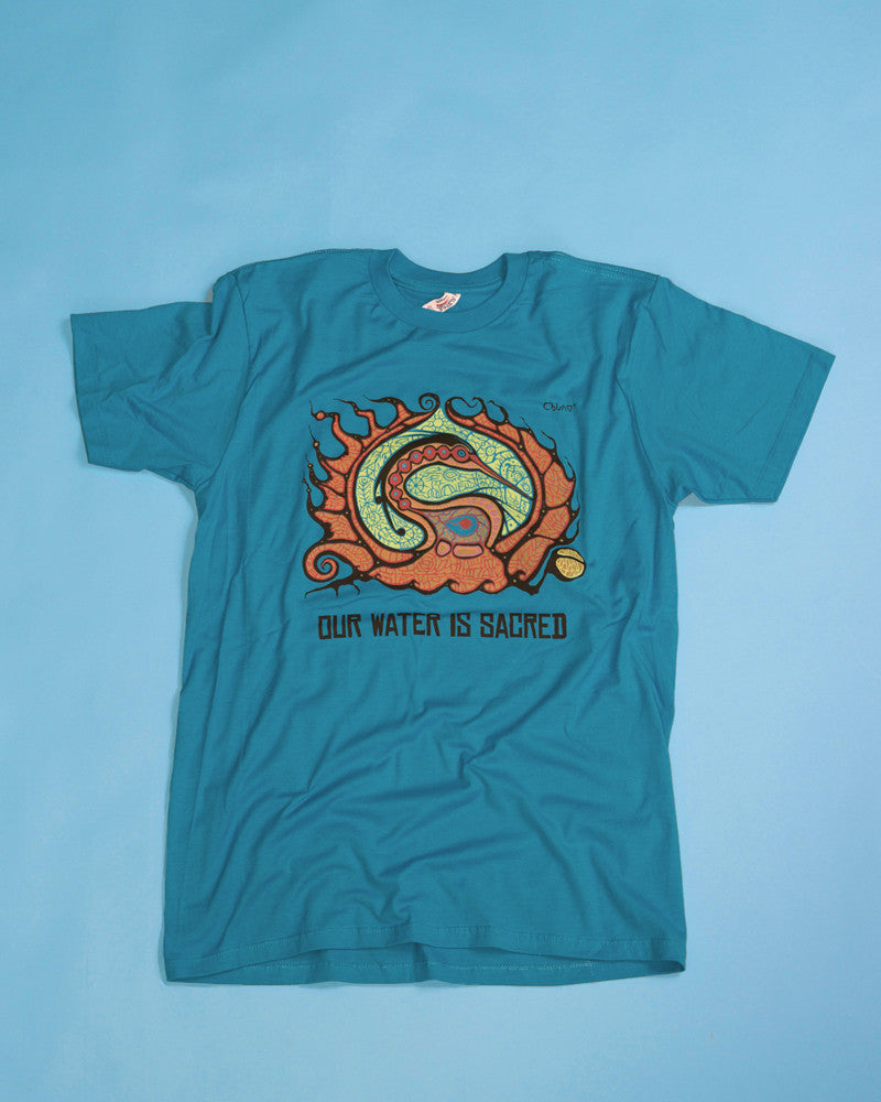 Turquoise t-shirt with woodland style painting of a Crane by Ojibwa artist Donald Chretien. Under the painting are the words: Our Water is Sacred. 5 colour, water-based silkscreen print on premium pre-washed soft cotton, Unisex sizes S-2XL